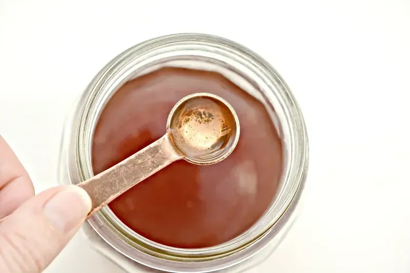 Adding orange extract to keto margarita mixture with measuring spoon