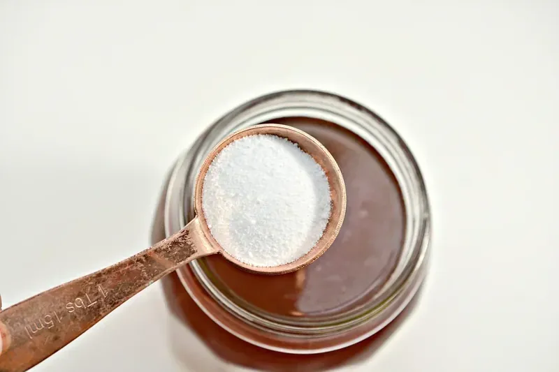 Adding sugar-free sweetener to margarita mixture with measuring spoon