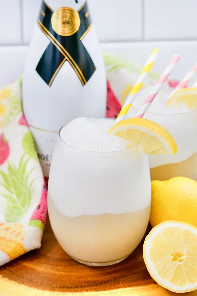 Single lemon champagne float with striped straw and fresh lemon half