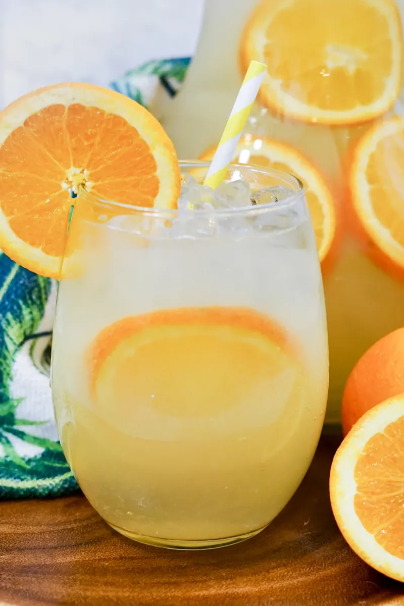 Golden mimosa sangria in glass with orange garnish