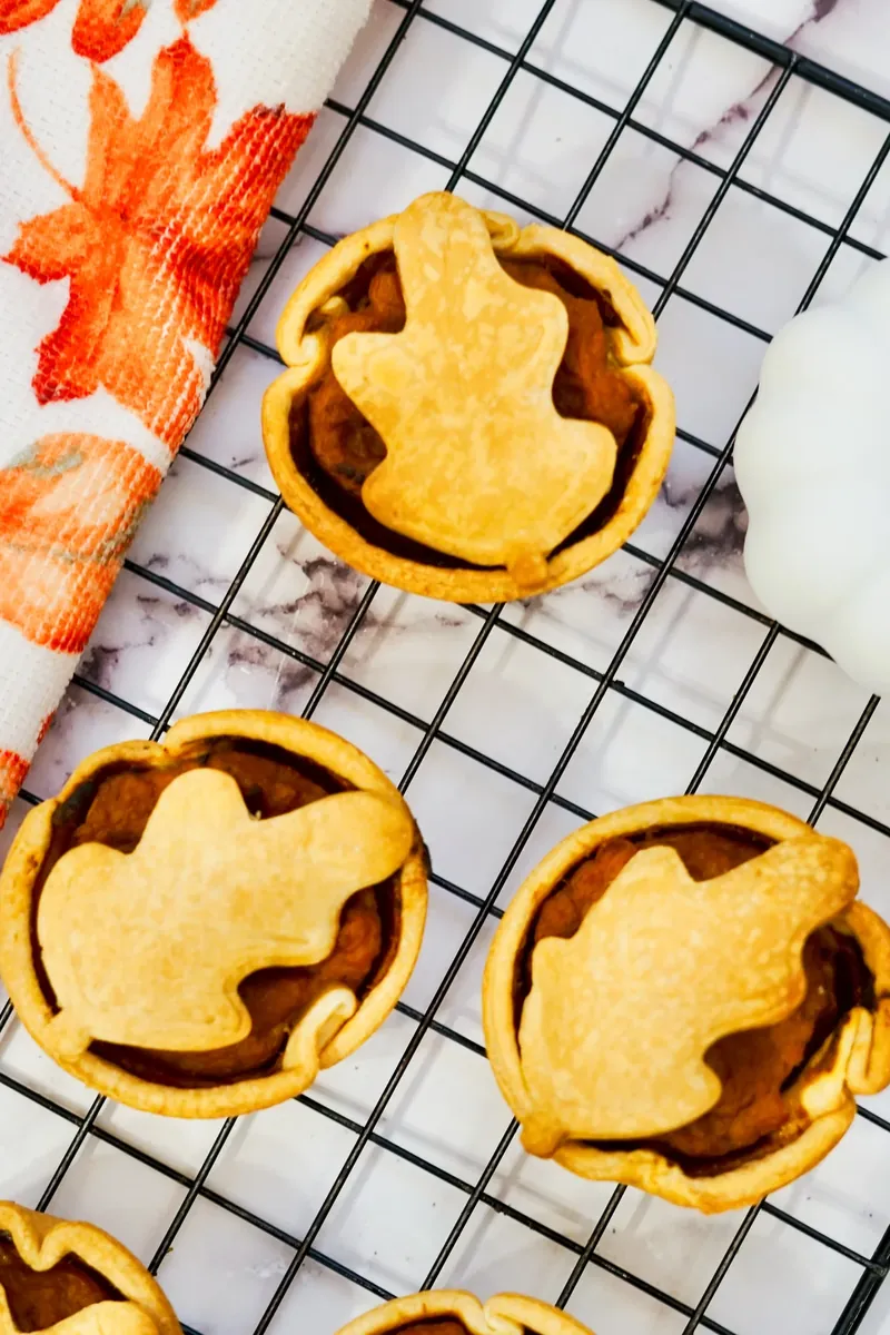 Close up view of mini pumpkin pies showing golden crust and leaf decorations