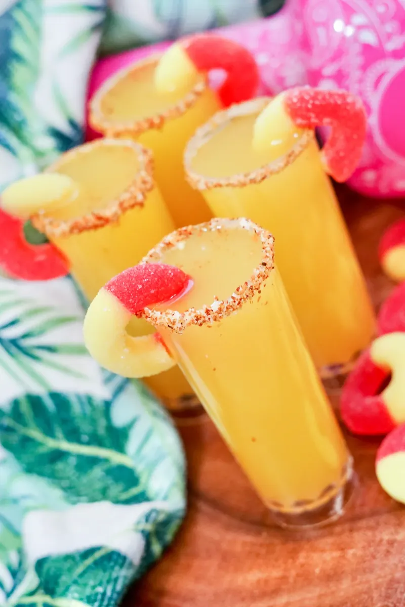 Beautiful golden peach margarita shooters with colorful garnishes
