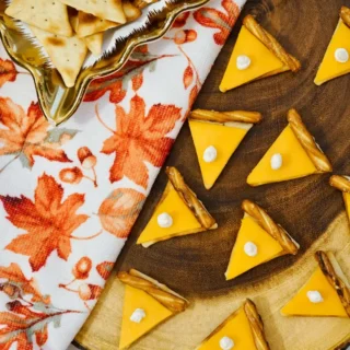 Completed pie cheese crackers arranged on wooden board with fall napkin