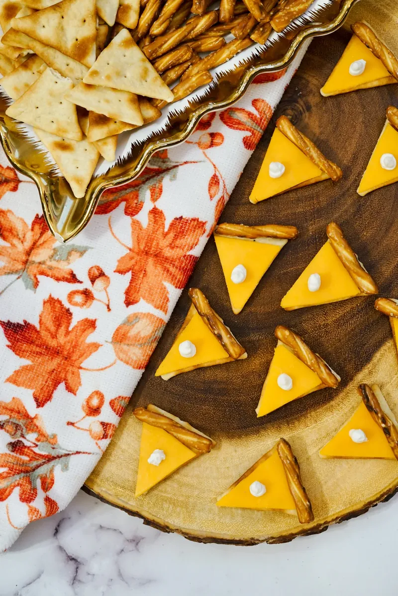 Completed pie cheese crackers arranged on wooden board with fall napkin