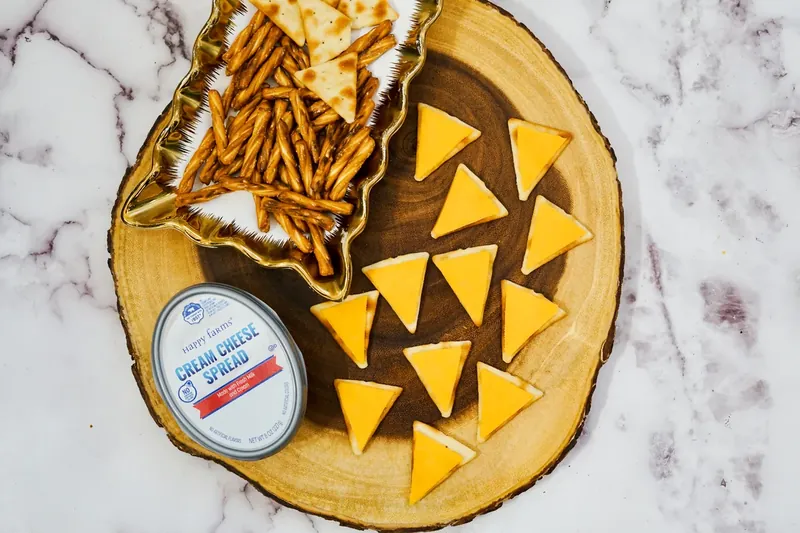 Triangle cheddar cheese pieces arranged on crackers with cream cheese