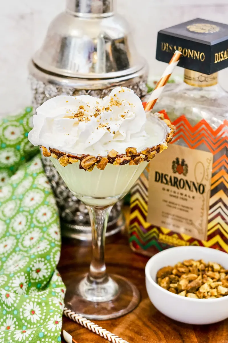 Close-up of pistachio martini showing whipped cream topping with golden pistachio garnish