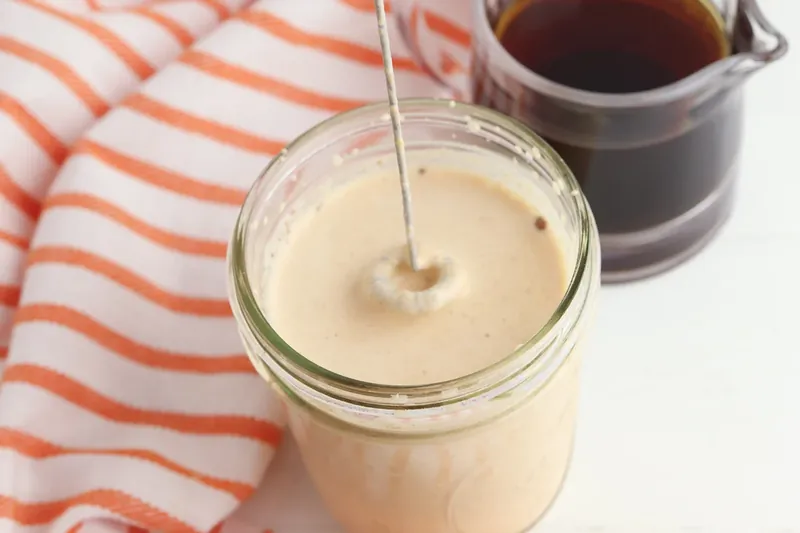 Milk frother blending pumpkin cream mixture in jar