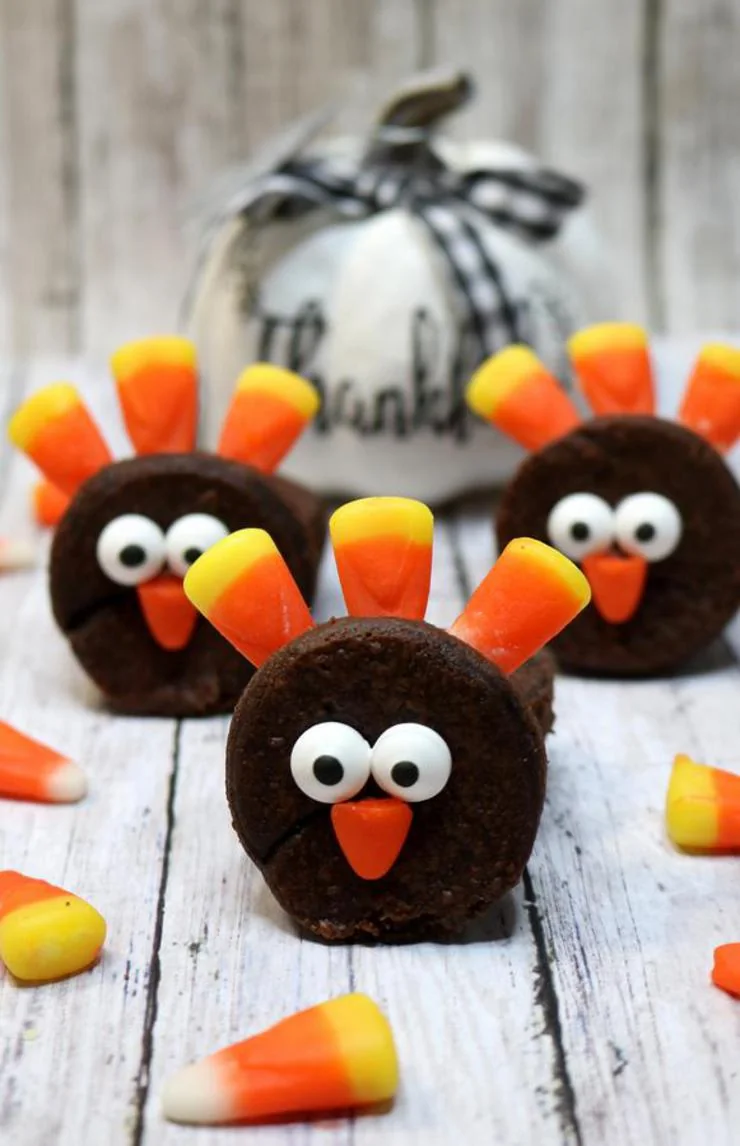 Chocolate turkey cookies decorated with candy corn feathers and googly eyes for Thanksgiving party favors