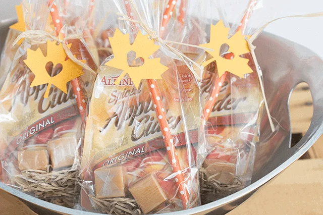 Clear favor bags with caramel candies tied with orange striped ribbons and maple leaf tags