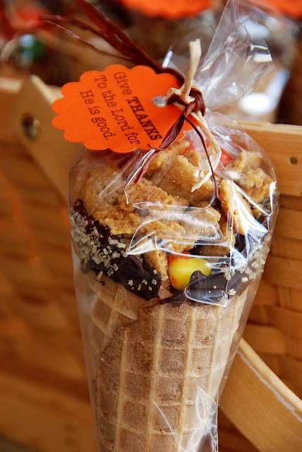 Waffle ice cream cones filled with fall candies wrapped in cellophane with orange thanksgiving tags