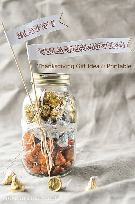 Mason jars layered with orange and brown candies topped with Happy Thanksgiving pennant flags