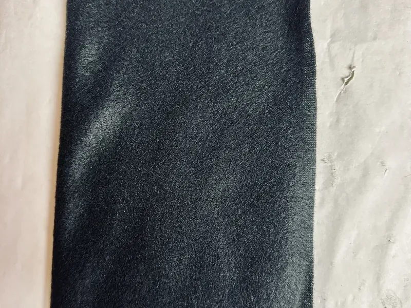 Black fleece scarf folded in half lengthwise on white surface ready to be cut to size