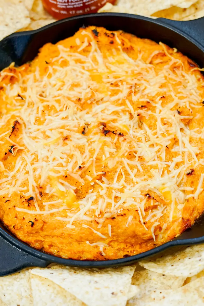 Close up view of melted cheesy honey sriracha chicken dip in cast iron skillet