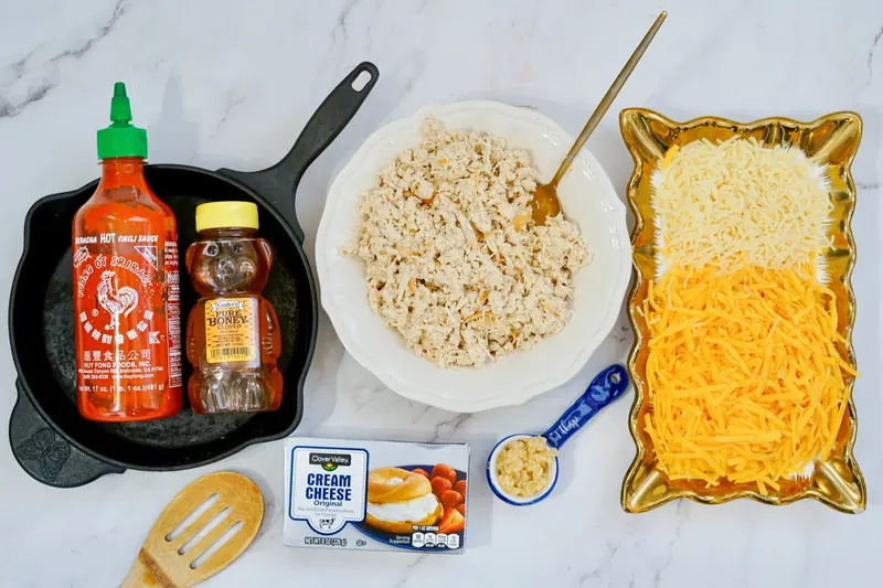 Ingredients for honey sriracha chicken dip including shredded chicken, sriracha, honey, and cheeses