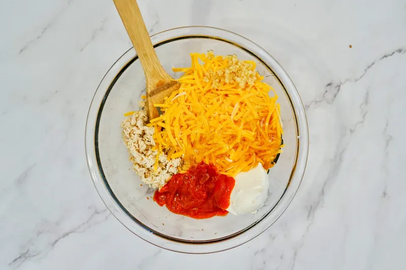 Mixed honey sriracha chicken dip ingredients in glass bowl ready for skillet