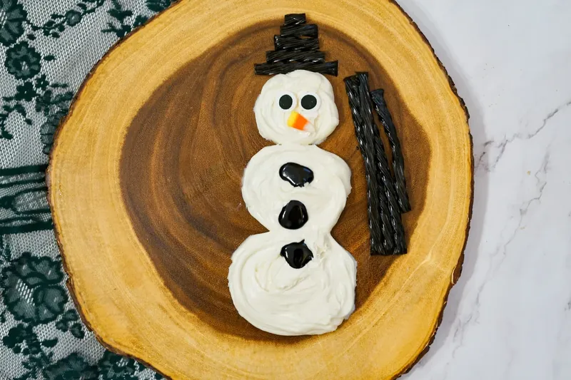 Black Twizzlers arranged to form hat on top of frosting snowman head