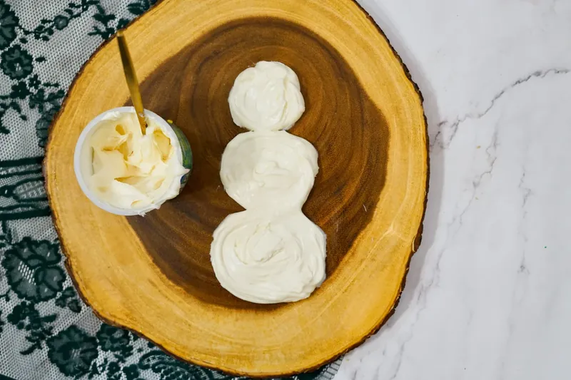 Three circles of white frosting piped on wooden board to form snowman body shape