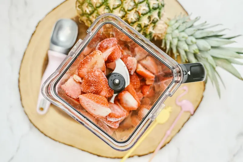 Frozen strawberries in blender pitcher ready for blending