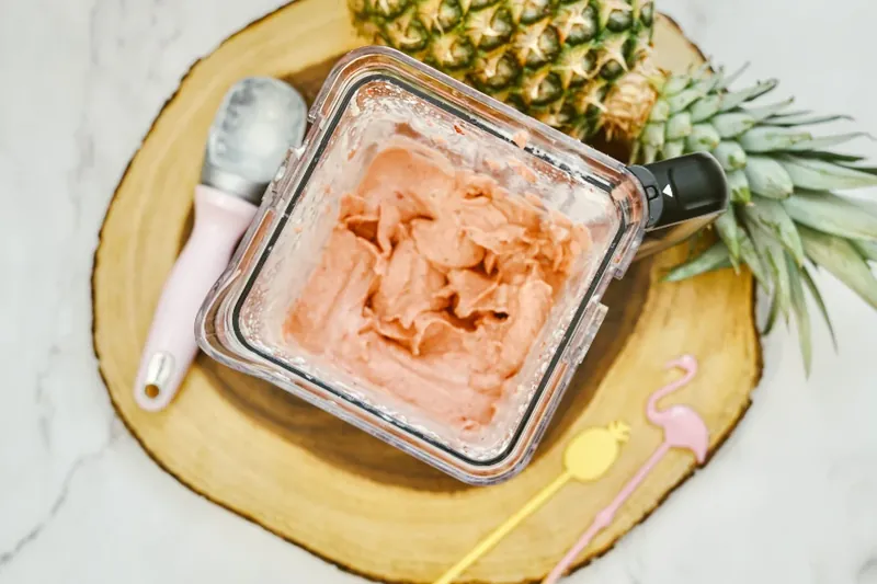 Strawberry dole whip served in margarita glass with tropical umbrella and pineapple garnish