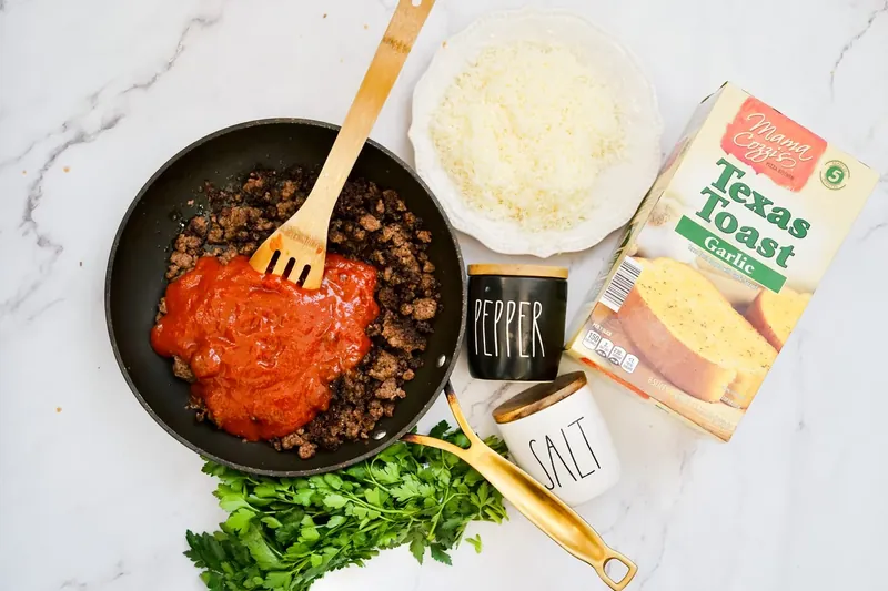 Ground beef in skillet with sloppy joe sauce being added