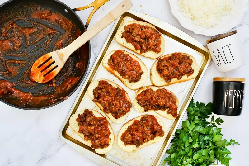 Texas toast topped with sloppy joe meat mixture on baking sheet