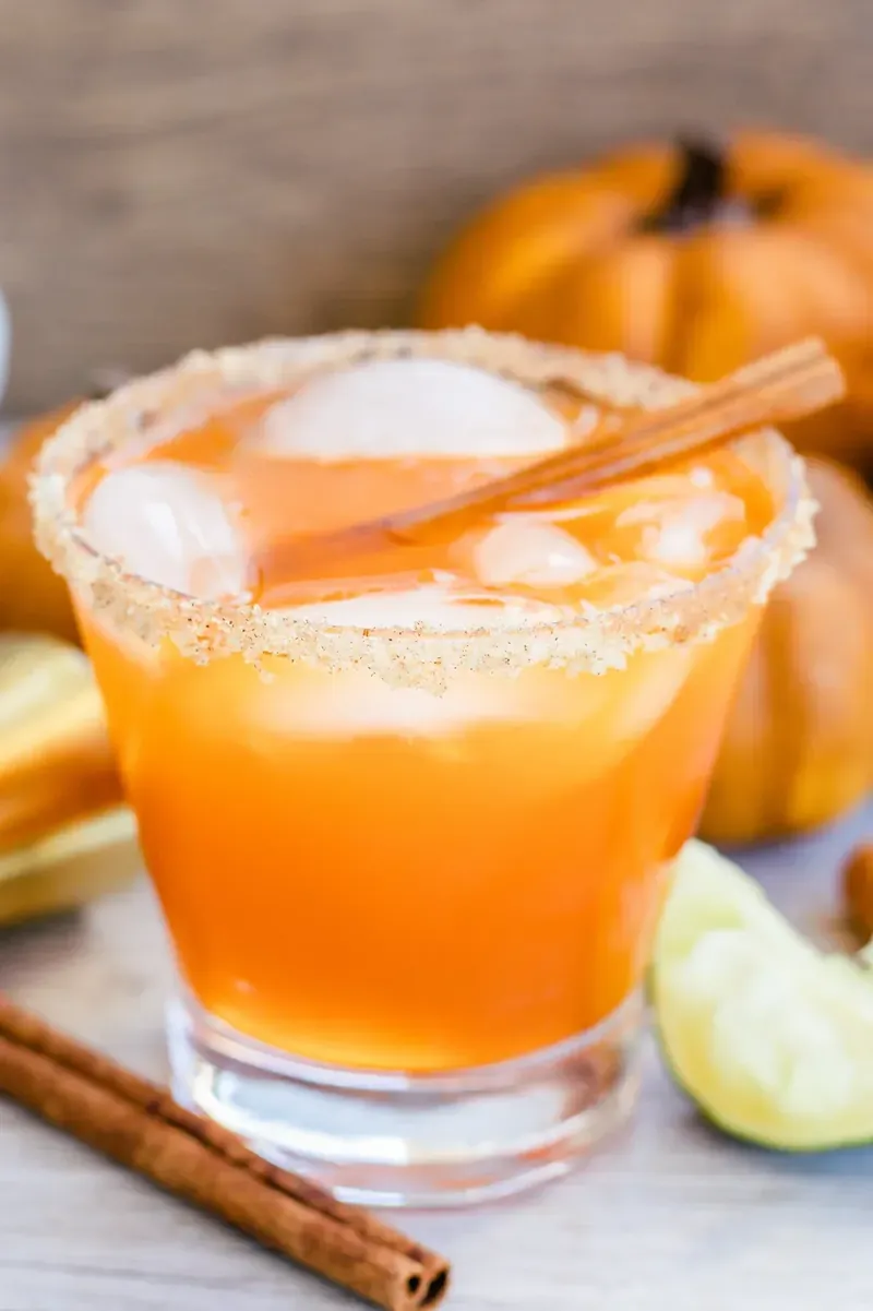 Orange thanksgiving margarita with cinnamon stick and lime garnish