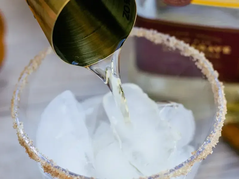Ice being added to cinnamon sugar rimmed cocktail glass