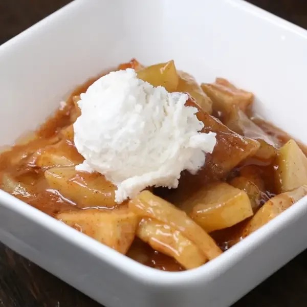 bowl of caramelized apple slices with vanilla ice cream scoop and caramel sauce