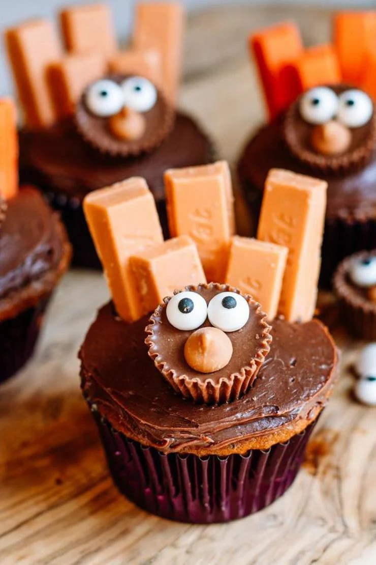 chocolate cupcakes decorated as turkeys with candy eyes, orange wafer feathers, and chocolate frosting