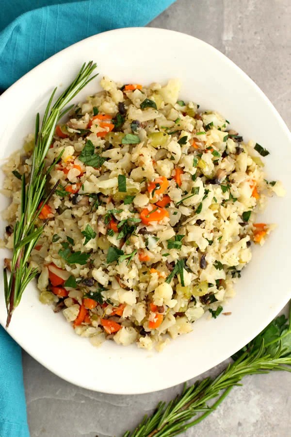 bowl of herb cauliflower rice with colorful vegetables and fresh rosemary garnish