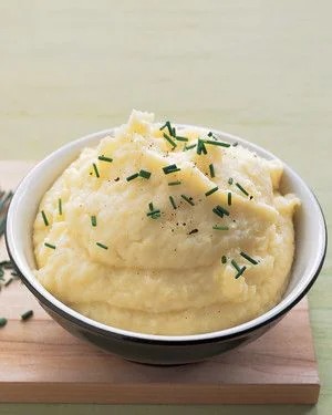 bowl of creamy mashed potatoes garnished with fresh chives and butter