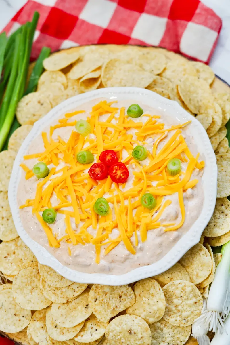 Complete TikTok boat dip spread with dip, tortilla chips, and fresh green onions on wooden board