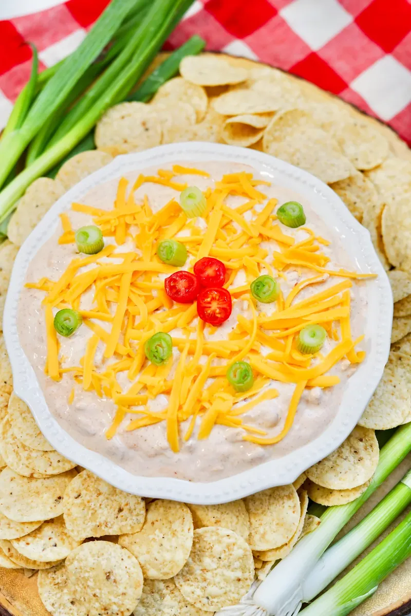 TikTok boat dip surrounded by tortilla chips on checkered tablecloth, ready for serving