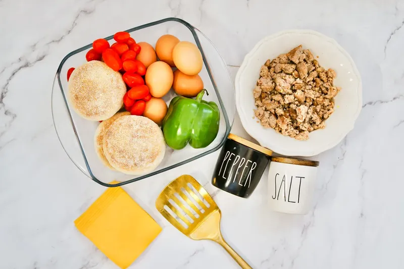 Ingredients for TikTok breakfast sandwich hack including English muffins, eggs, sausage, and vegetables