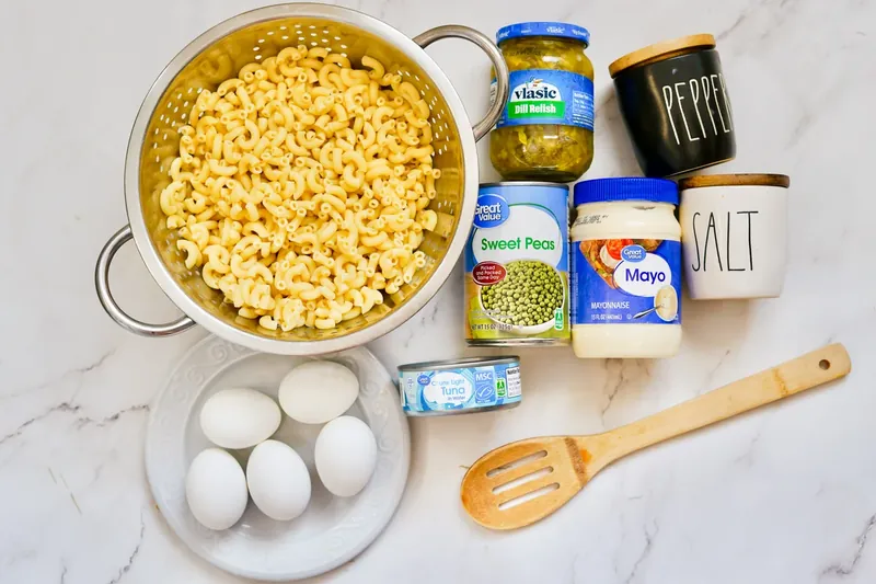 Tuna mac salad ingredients including cooked pasta, tuna, eggs, peas, relish and mayo