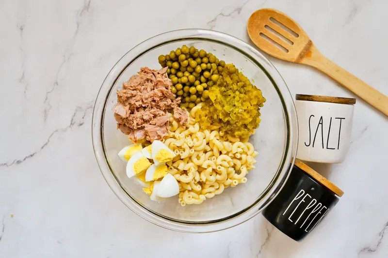 Bowl with pasta, tuna, chopped eggs, peas and relish before adding mayo