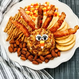 Turkey cheese ball appetizer with bacon feathers on festive platter with crackers and nuts