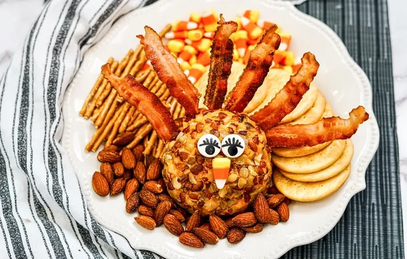 Completed turkey cheese ball with bacon feathers, candy eyes, and candy corn beak