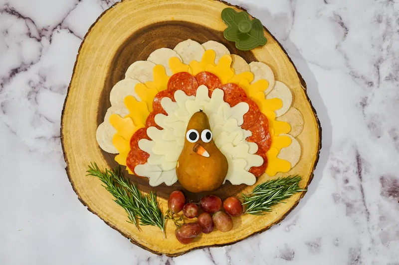 Completed turkey cheese plate with pear body, candy eyes, and red jellybean beak