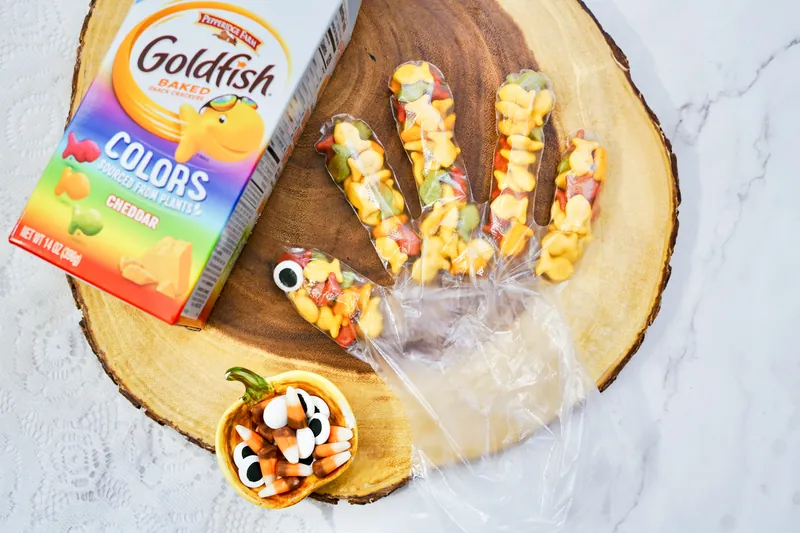 Plastic glove with fingers filled with colorful goldfish crackers creating turkey feathers