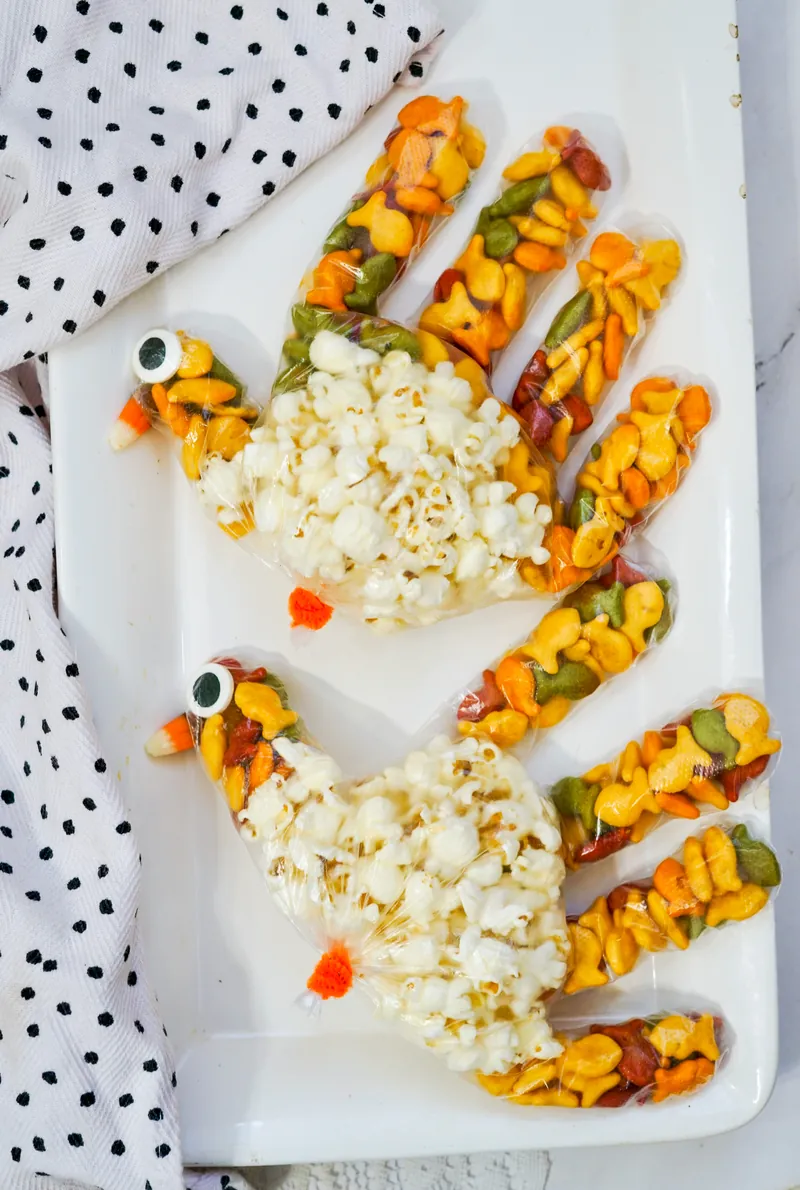 Handmade turkey treat bags with popcorn bodies and snack-filled tail feathers for Thanksgiving crafts
