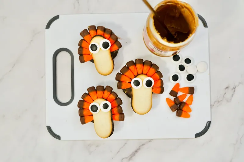 Turkey cookies with candy eyes being added to create faces