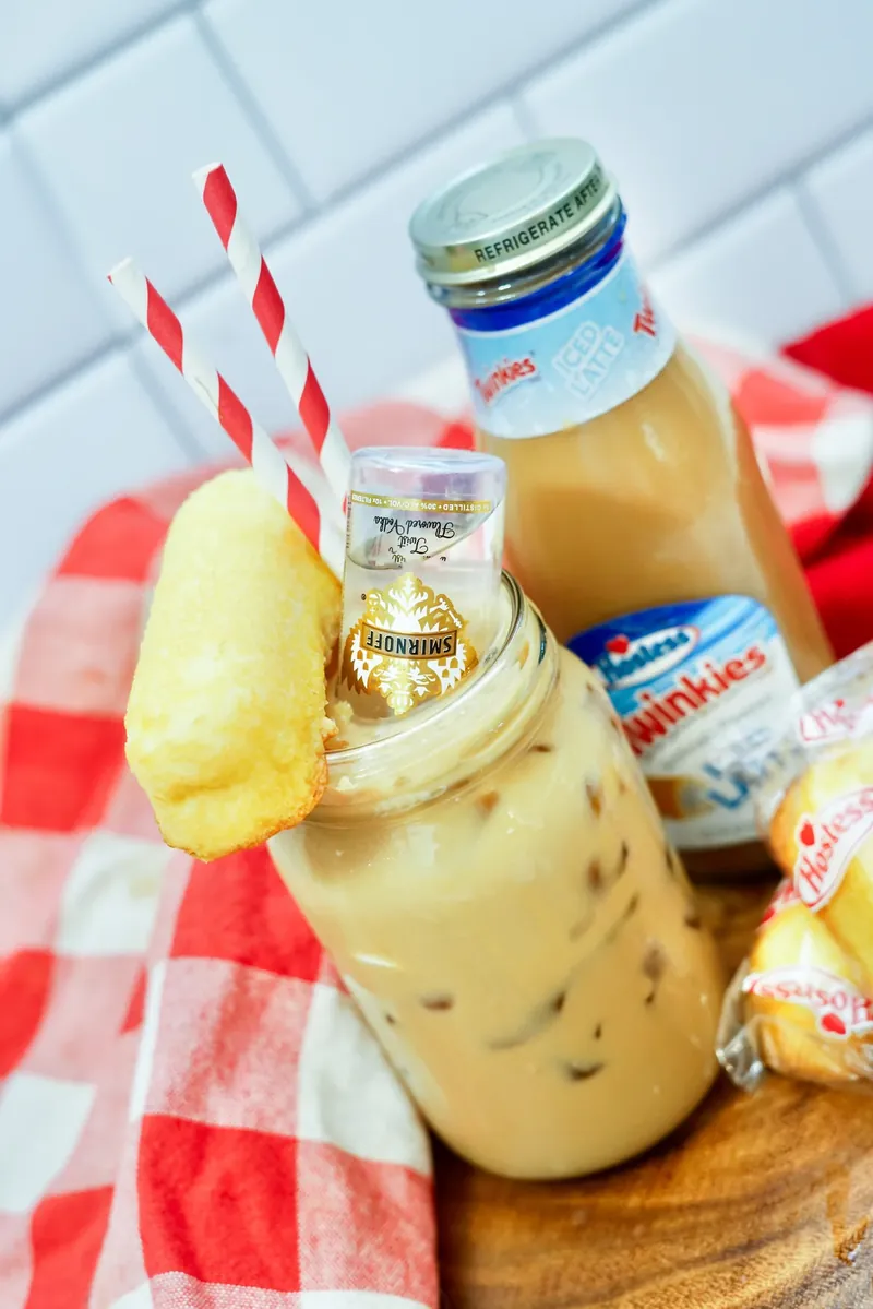 Stylized Twinkie boozy iced latte with red striped straws and checkered napkin