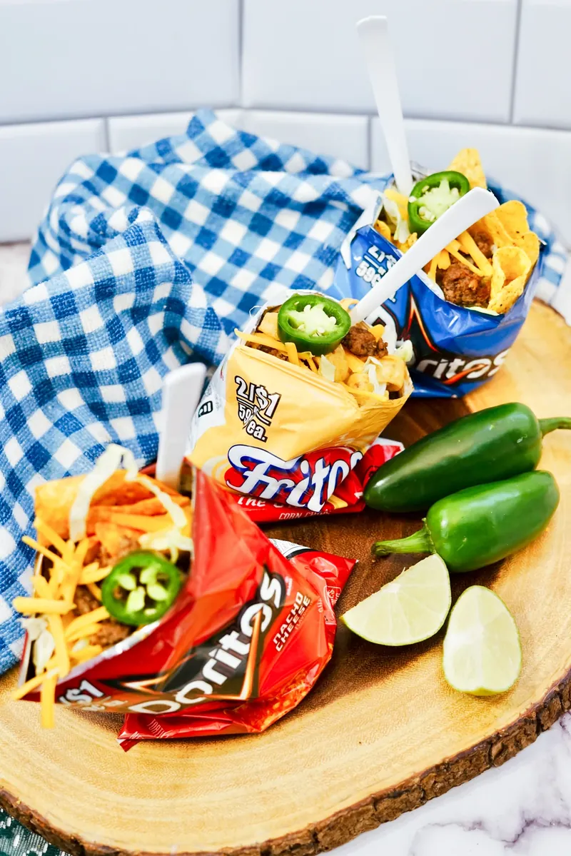 Walking tacos made with different chip varieties on wooden serving board