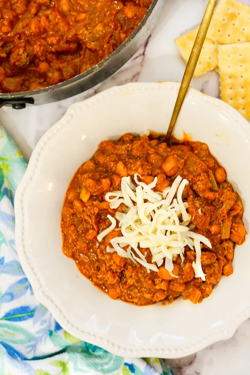 Finished Wendy's copycat chili in bowl with cheese topping and crackers