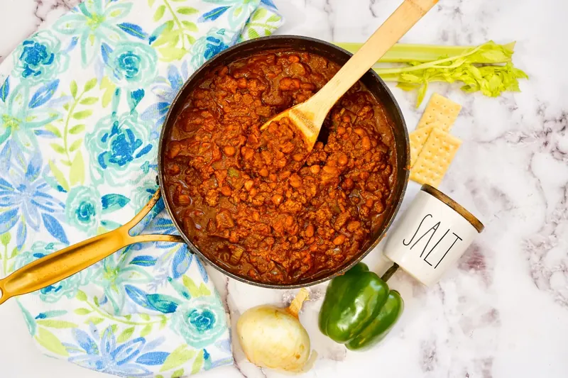 Wendy's copycat chili simmering in pot with wooden spoon