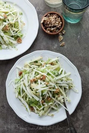 Fresh fennel and apple salad with walnuts and herbs on white plates