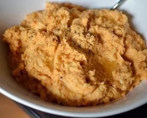 Creamy whipped sweet potato mash in white serving bowl with spoon