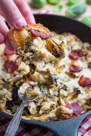 Creamy Brussels sprouts and bacon gratin being served from cast iron skillet