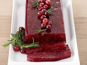 Elegant molded cranberry sauce loaf garnished with fresh cranberries and rosemary on white platter